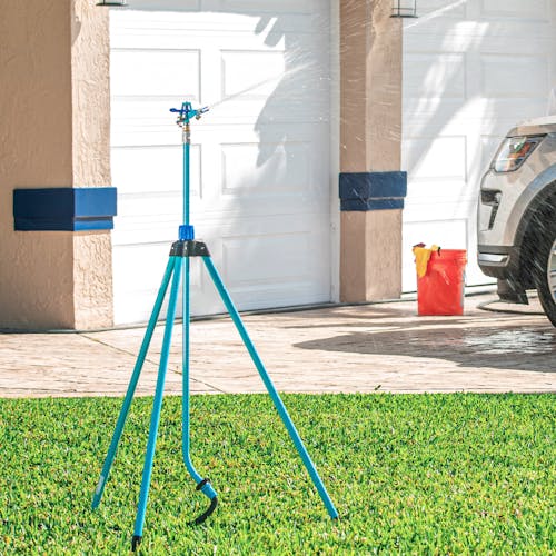 Aqua Joe 72-inch Indestructible Zinc Impulse 360-Degree Telescoping Tripod Sprinkler watering a lawn.