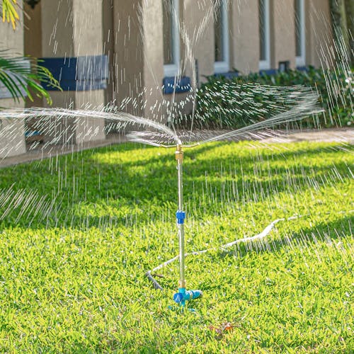 Aqua Joe 3-Arm Brass Rotary 360-Degree Telescoping Sprinkler watering a lawn.