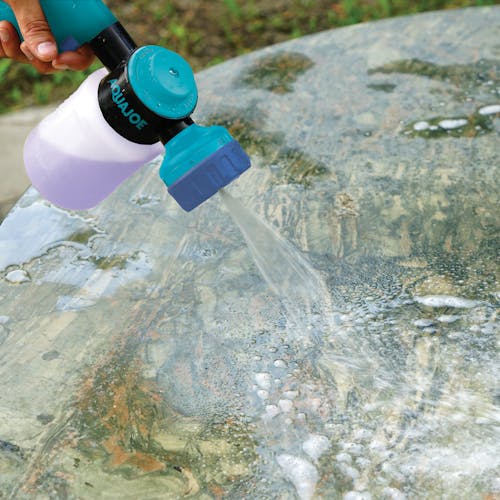 Aqua Joe 17-ounce Hose-Powered Multi Spray Gun with Quick Change Soap to Water Dial cleaning an outdoor table countertop.