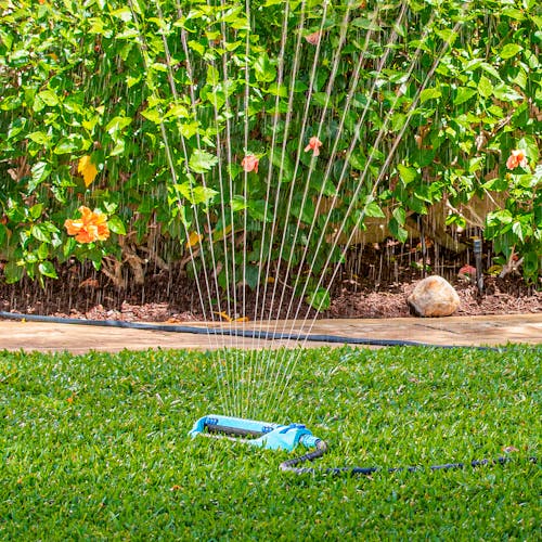 Aqua Joe 20-nozzle Indestructible Metal Base Oscillating Sprinkler watering a lawn.