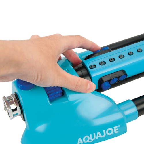 Person adjusting the spray range on the Aqua Joe 20-nozzle Indestructible Metal Base Oscillating Sprinkler.