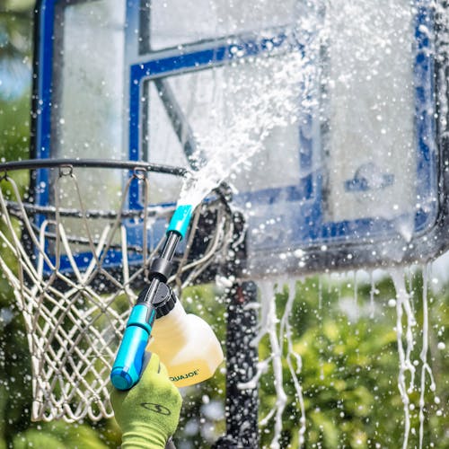 Aqua Joe 2-in-1 Hose-Powered Adjustable Foam Cannon Spray Gun Blaster being used to clean a basketball hoop.