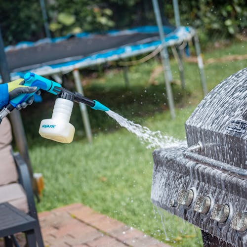 Aqua Joe 2-in-1 Hose-Powered Adjustable Foam Cannon Spray Gun Blaster being used to clean a grill.