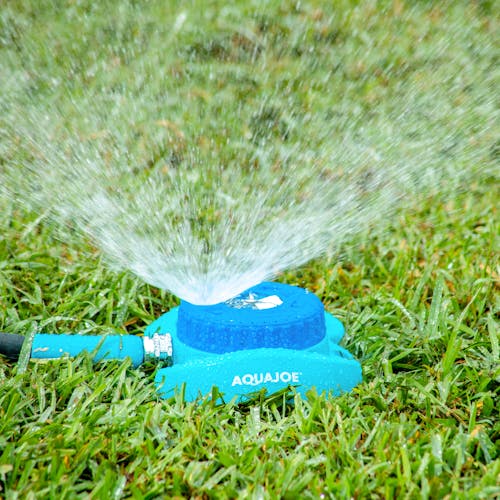 Close-up of the Aqua Joe Indestructible Metal Turret Sprinkler watering the lawn.
