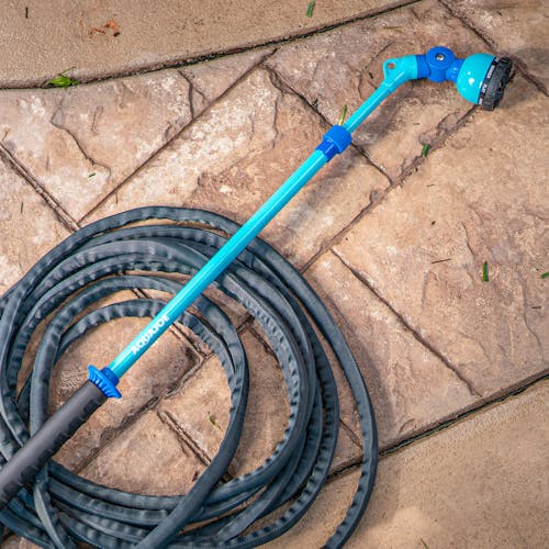 Aqua Joe 53-inch Telescoping Watering Wand connected to a hose on the ground.