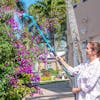 Woman using the Aqua Joe 53-inch Telescoping Watering Wand to water flowers up high on a bush.