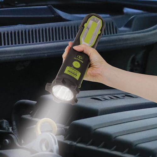 Headlight on the Auto Joe Cordless 12-Volt High Performance Vehicle Jump Starter being used to see a car engine.