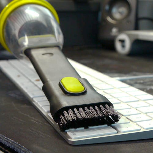 Brush being used with the vacuum to clean a computer keyboard.