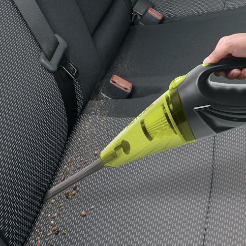 Auto Joe 12-Volt Portable Car Vacuum Cleaner witht he crevice nozzle being used to clean the tight crevices of the car ceats.