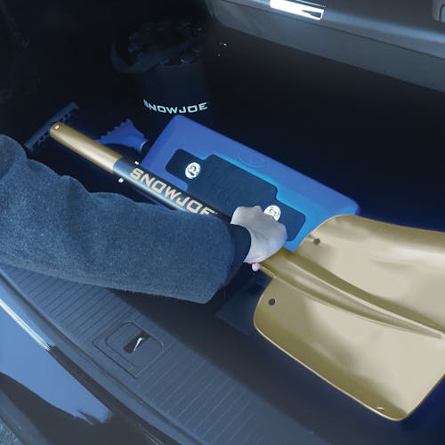 Person placing the Snow Joe 32-inch gold-color Aluminum Compact Utility Shovel in a car trunk.