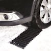Snow Joe 24-inch Thermoplastic Rubber TrackAssist Non-Slip Traction underneath a car tire.