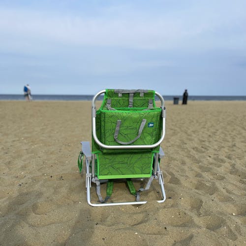 Rear view of the green banana leaves backpack beach chair on the sand.