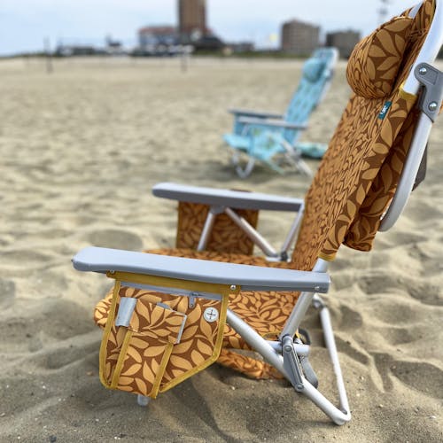 Side view of the Backpack Aluminum Amber Leaf Beach Chair on the beach showing its side pocket.