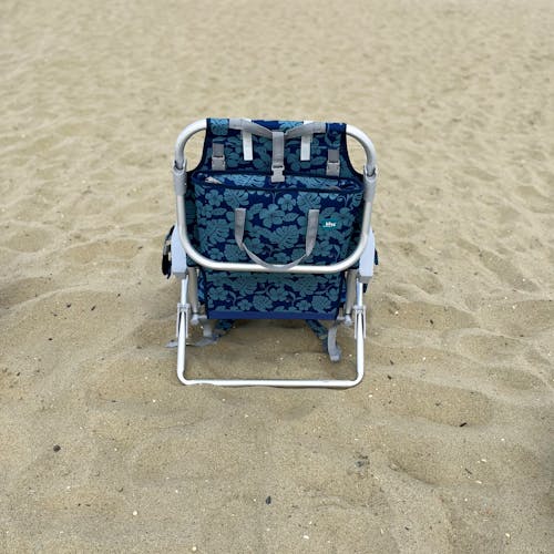 Rear view of the blue flower backpack beach chair on the sand.