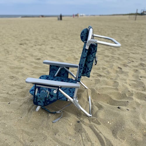 Side view of the blue flower backpack beach chair on the sand.