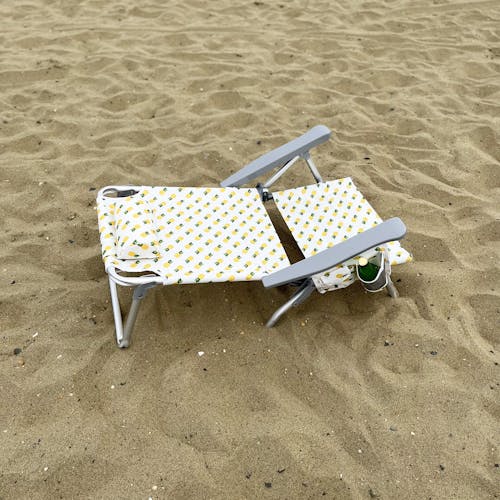 Folding pineapple beach chair fully reclined on the sand.