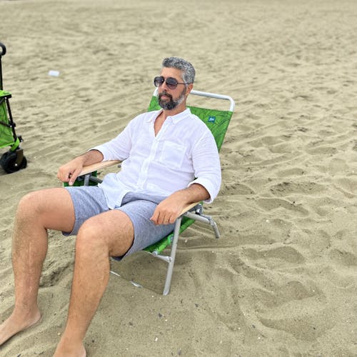 Man with sunglasses relaxing on the beach in the foldable green banana leaves beach chair.