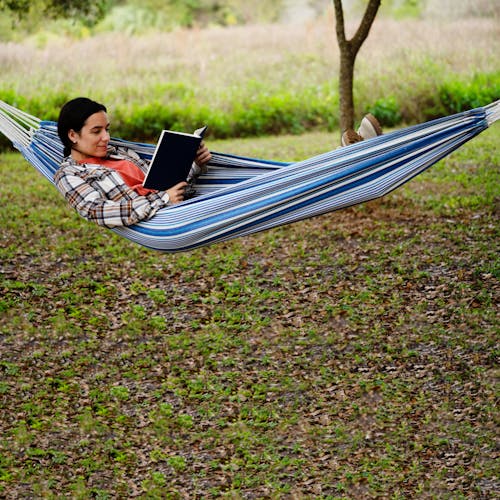 Woman relaxing in the 40-inch hammock outside while reading a book.
