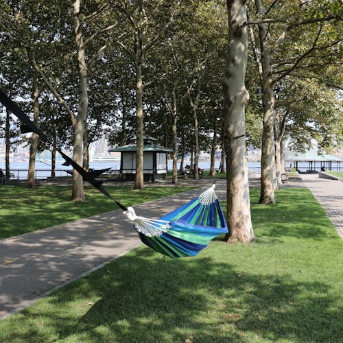 Bliss Hammocks 40-inch Wide Seabreeze Stripe Hammock in a Bag hanging between two trees in a park.