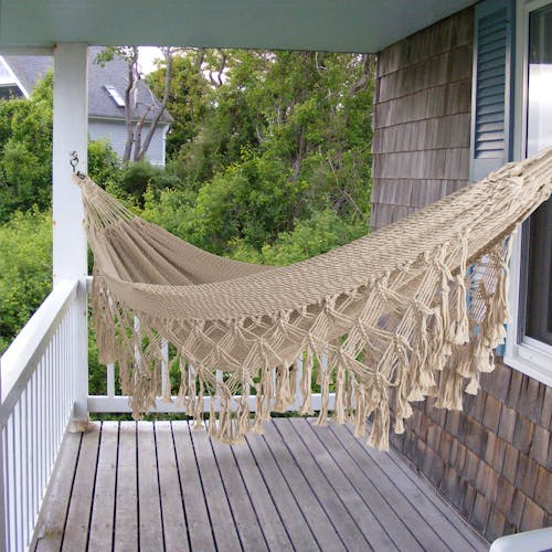 Bliss Hammocks 40-inch Wide Brazilian Style Rope Hammock with fringe hanging on a front porch.