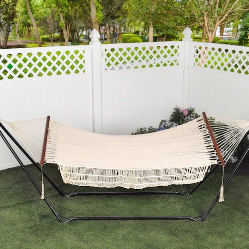 48-inch rope hammock hanging from a stand in a back yard.