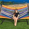 Girl sitting in the Bliss Hammocks 60-inch Wide Multi-Color Rope Hammock.