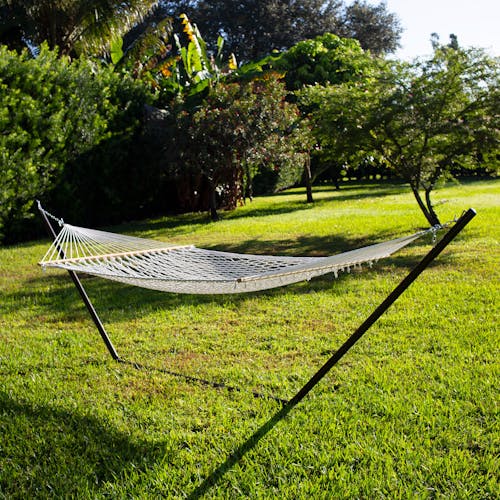 60-inch Wide White Cotton Rope Hammock secured to a stand outside on grass.