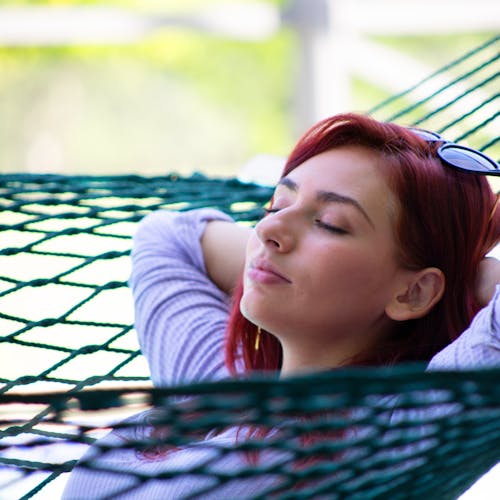 Woman relaxing in the Bliss Hammocks 60-inch Wide Green Cotton Rope Hammock.