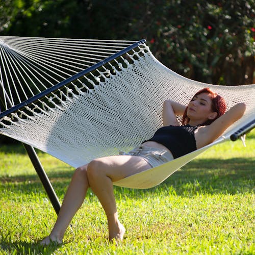 Woman sitting and laying back in the Bliss Hammocks 55-inch Wide 2-Person Weekender Deluxe Hammock.
