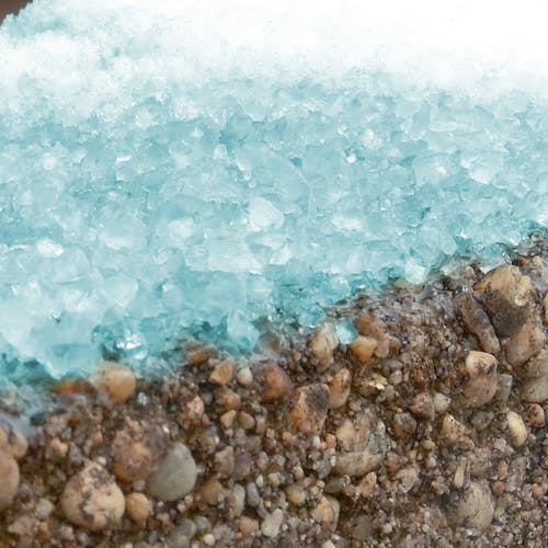 Close-up of the blue heat calcium blend ice melt melting snow.