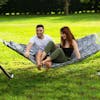 Couple sitting outside on the 55-inch Hexagonal Quilted Hammock.