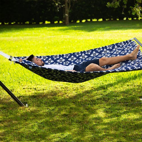 Man laying spread out across the Bliss Hammocks 55-inch Blue Flowers Quilted Hammock.
