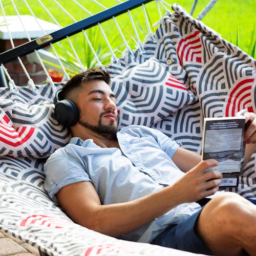 Man reading a book while laying in the 55-inch Red and Grey Quilted Hammock.