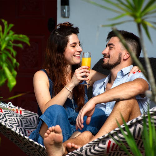 Couple sitting in the 55-inch Red and Grey Quilted Hammock with a drink in the girls hand.