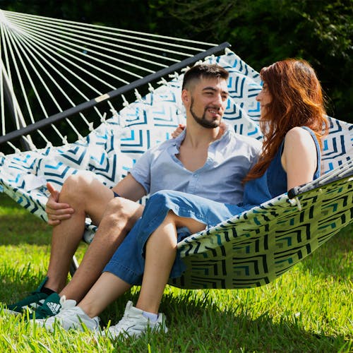 Couple sitting outside on the Bliss Hammocks 55-inch Blue Geo Diamond Quilted Hammock.