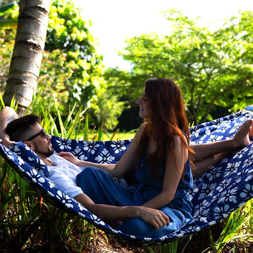 Couple relaxing outside on the Bliss Hammocks 55-inch Blue Flowers Quilted Hammock.