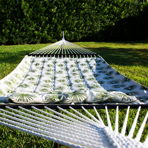 Depth of field shot of the 55-inch Green Burst Quilted Hammock in the sun.