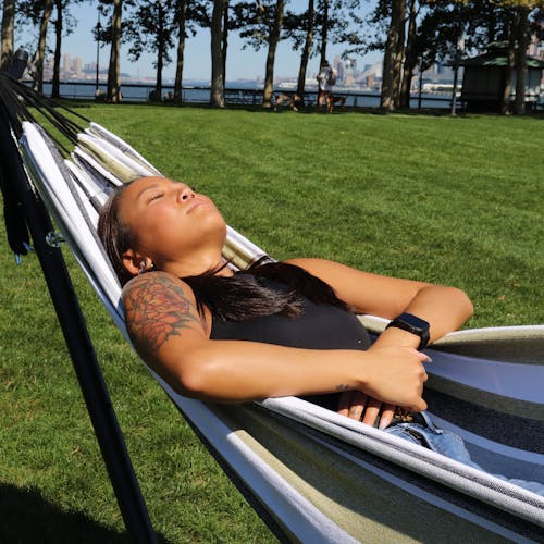 Girl laying in the sun on the 60-inch Hampton Stripe hammock and stand.