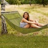 Woman sitting outside in the Bliss Hammocks 55-inch Wide 2-Person Reversible Quilted Hammock.