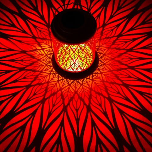 Lantern with diamond leaf design creating a red pattern on the surface around it.