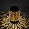 Lantern with phoenix feather design creating a light pattern on the surface around it.