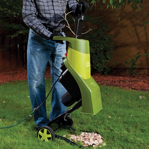 Person using the Sun Joe 14-amp electric wood chipper to make wood chips.