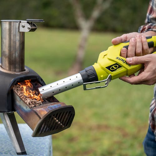 Sun Joe 24-Volt cordless electric fire starter and barbeque lighter being used to ignite a portable grill.