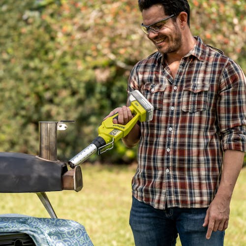 Man using the Sun Joe 24-Volt cordless electric fire starter and barbeque lighter to light his grill.
