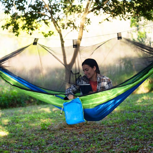 Woman sitting outside in the Bliss Hammocks 54-inch wide Mermaid-variation Camping Hammock with the mosquito net zippered shut.