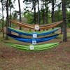 4 Bliss Hammocks Camping Hammocks of different variations hung above one another between two trees.