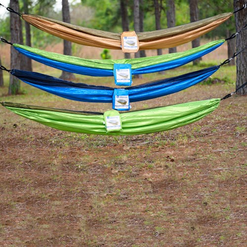 4 Bliss Hammocks Camping Hammocks of different variations hung above one another between two trees.