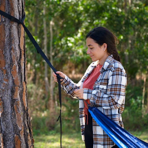 Woman connected the camping hammock to the tree strap.
