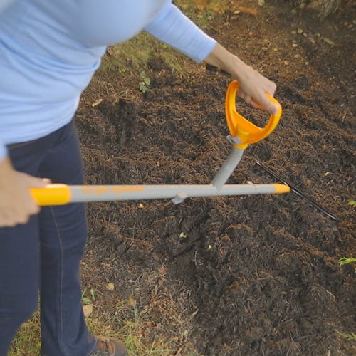 Person using the ErgieSystems 55-inch Steel Shaft Strain Reducing Bow Rake with 16 tines to rake soil.