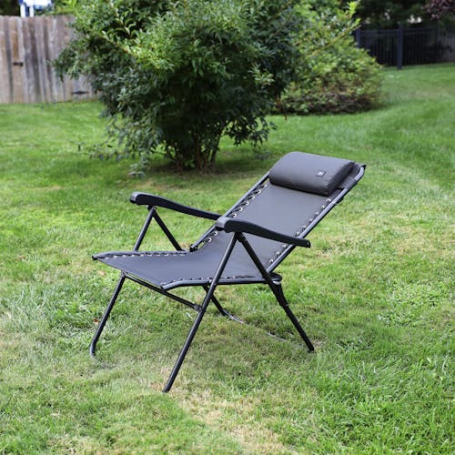 Angled view of a reclined 26-inch Black Reclining Sling Chair on a lawn.